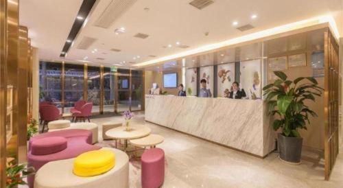 a lobby with a bar with pink chairs and tables at Lavande Hotels Wuhan Guanggu Yangjiawan Metro Station in Wuhan