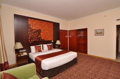a hotel room with a large bed and a chair at Dubai Grand Hotel by Fortune, Dubai Airport in Dubai