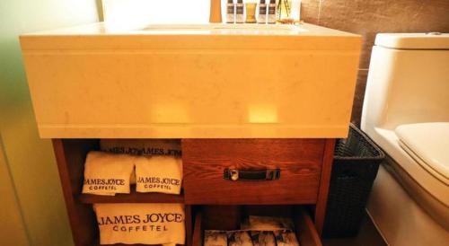 a bathroom sink with a wooden cabinet underneath it at James Joyce Coffetel Kunming Railway Station Huancheng Nan Road Metro Station in Kunming