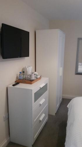 a bedroom with a white dresser with a tv on the wall at The City Arms in Wells