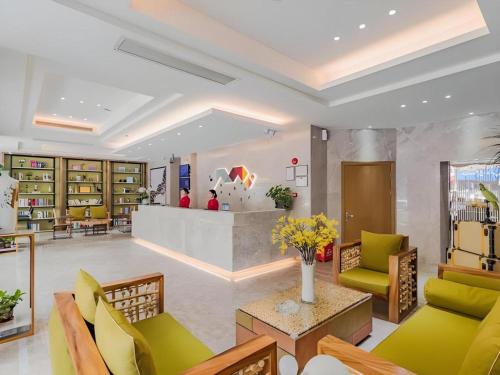 a lobby of a library with green chairs and a counter at Borrman Hotel Huizhou West Lake Shuidong Street in Huizhou
