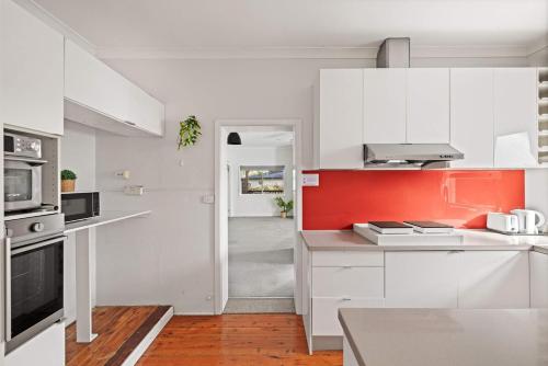 a kitchen with white cabinets and an orange wall at Freshly Modernized Single Room- Well-Connected Suburb Shared Bathroom in Epping
