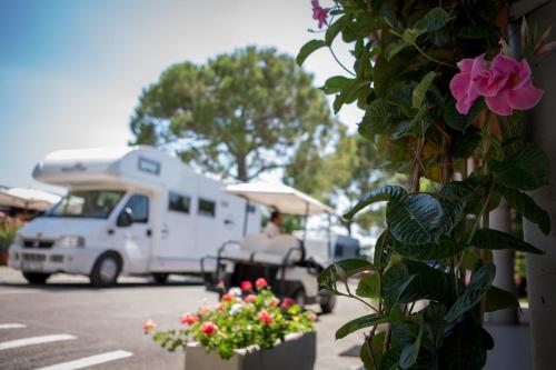 a white truck parked in a parking lot with flowers at Camping Fossalta in Lazise