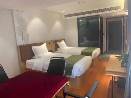 a hotel room with two beds and a chair at GreenTree Inn Express Datong High-Speed Railway Station Old City Wall in Datong