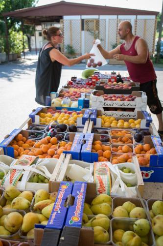 two people standing in front of a display of fruit at Camping Fossalta in Lazise