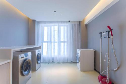 a laundry room with a washing machine and a window at Echarm Hotel Nanning the MixC Dongmeng Business District in Nanning
