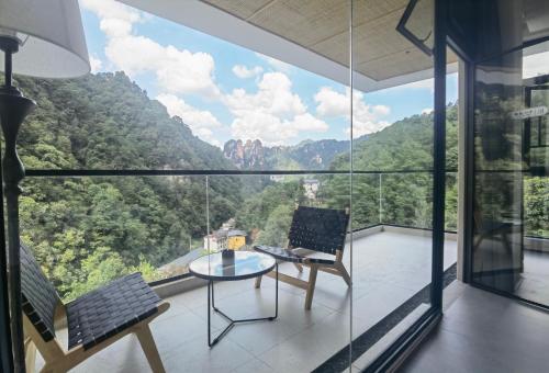 a room with a table and a laptop on a balcony at Zhangjiajie MUYE HOTEL in Jiawan