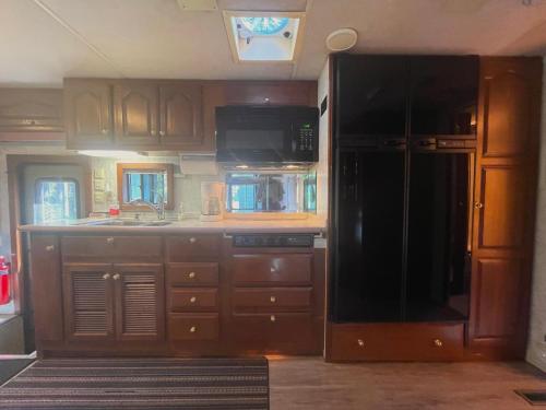a kitchen with wooden cabinets and a black refrigerator at The Great Escape - Shirley in Sooke