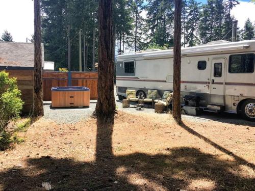 an rv parked next to trees in a yard at The Great Escape - Shirley in Sooke