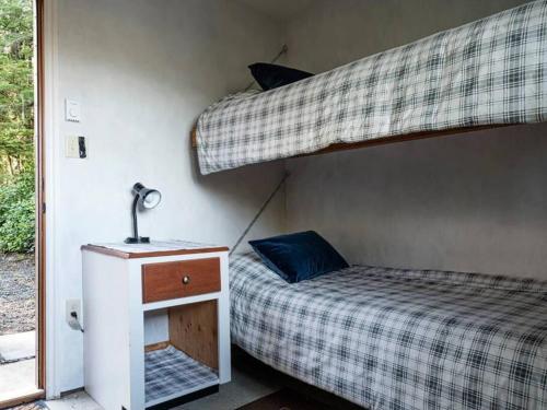 a bedroom with two bunk beds and a lamp on a night stand at The Great Escape - Port Renfrew in Port Renfrew