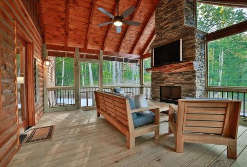 a screened in porch with a fireplace and a tv at Mountain Hideaway with Hot Tub & Fire Pit in Mineral Bluff
