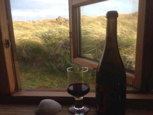 una bottiglia di vino e un bicchiere su un tavolo vicino a una finestra di Scenic Holiday Home In Skagen a Skagen