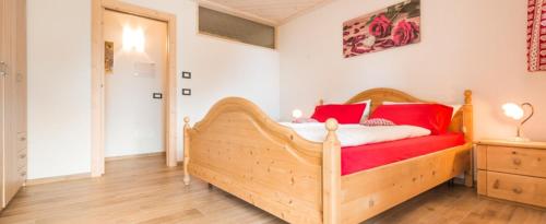 - une chambre avec un lit en bois et des oreillers rouges dans l'établissement Baita del Beniamino, à Roncegno