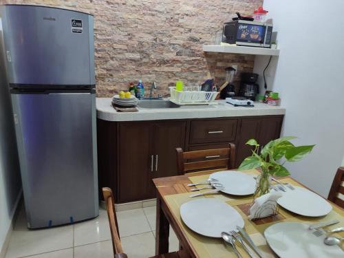 a kitchen with a stainless steel refrigerator and a table at Chan Kiin Departamentos in Valladolid