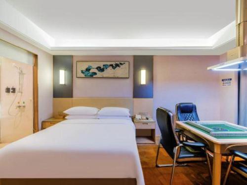 a hospital room with a bed and a table and chairs at Vienna Hotel Guangdong Zhongshan Xiaolan High-Speed Railway Station in Zhongshan
