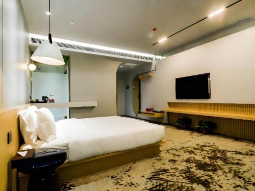 a bedroom with a bed and a flat screen tv at Borrman Hotel Jining High-tech Huangtun in Jining