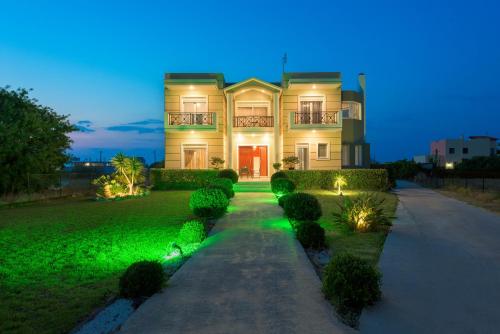 a large house with green lighting in front of it at Sunny Breeze Deluxe Villa Near Beach, Private Pool in Kremasti