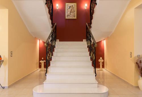 a staircase in a building with white stairs and red walls at Sunny Breeze Deluxe Villa Near Beach, Private Pool in Kremasti