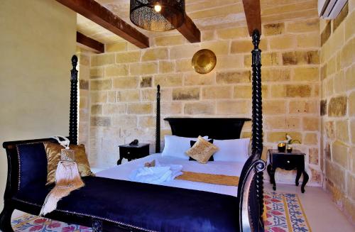 a bedroom with a black bed and a stone wall at Chapel 5 Boutique Suites B&B in Naxxar