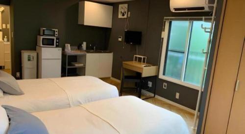 a bedroom with two beds and a kitchen with a window at HOSTEL LUND I -Oimachi- in Tokyo