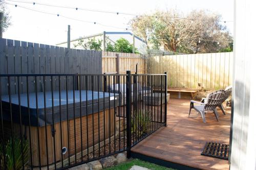 a fence in a backyard with a bench and a bed at A Lazy Marlin in Smiths Beach