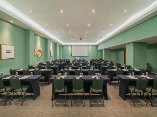 a conference room with tables and chairs and a screen at Grand Mercure Rio de Janeiro Copacabana in Rio de Janeiro