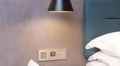 a light switch on a wall next to a bed at ZMAX Hotels Shenzhen Lianhuacun Metro Station in Shenzhen