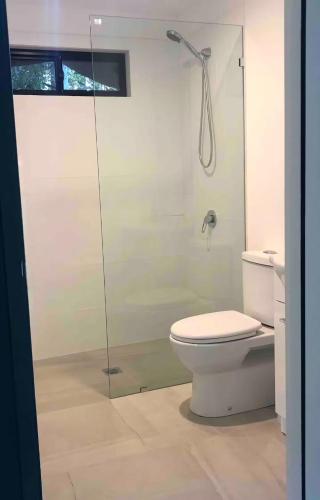 a bathroom with a toilet and a glass shower at Aura Glamping Bell Tent in Eumundi