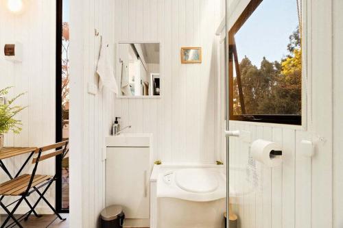 a small bathroom with a toilet and a window at The Whistling Frog by Tiny Away in Neerim South