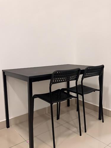 a black table with a black chair sitting next to it at Goldenstay Mutiara Ville Cyberjaya in Cyberjaya
