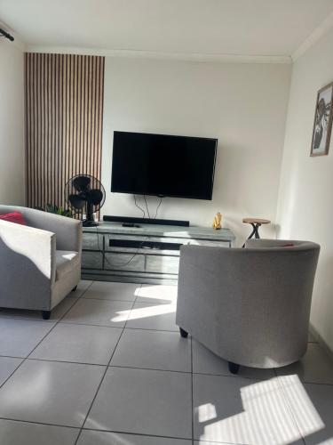 a living room with a flat screen tv on a wall at Relaxa Sleep & Go - Self Catering Accommodation in Cape Town