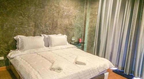 a bedroom with a large bed with white sheets at So Herbs at Home in Chiang Rai