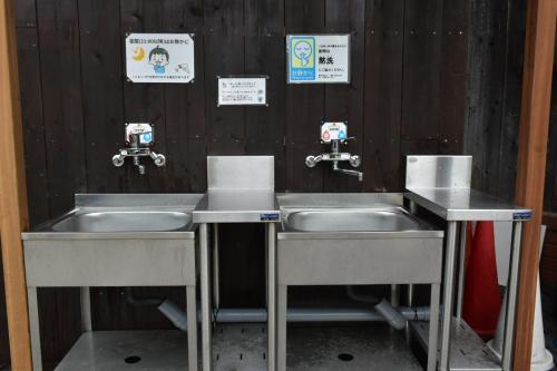 two sinks in a public restroom with signs on the wall at Star Forest Camp Hayama in Hayama