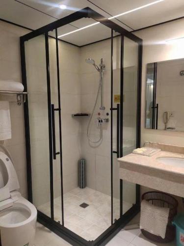 a bathroom with a shower and a toilet and a sink at Yanji Yanbian International Hotel in Yanji