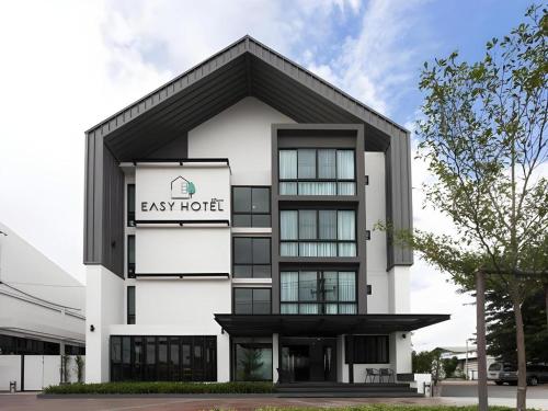 a large white building with a sign on it at Esy Hotel in Lamphun
