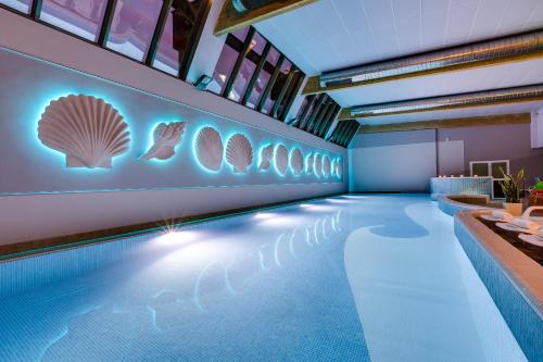 a swimming pool with a mural of seashells on the wall at Hotel Aurora Family & SPA in Międzyzdroje