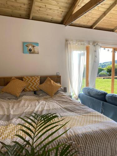 a bedroom with a bed and a couch and a window at The Cabin at Tedburrow rural retreat perfect for couples in Culmstock