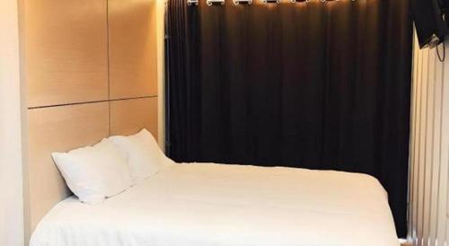 a bedroom with a white bed and a black curtain at Boxotel in Maha Sarakham