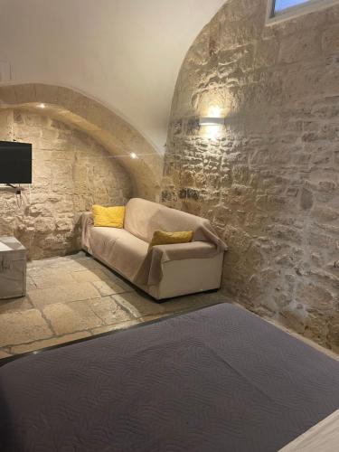a living room with a couch in a stone wall at Dimora Mazzini in Trani