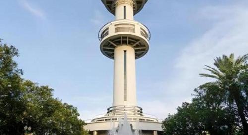 a tall tower in front of a building with trees at Sweet Hug Hotel in Suphan Buri