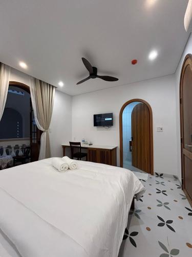 a bedroom with a white bed with a ceiling fan at Vang Anh Homestay Hoi An in Hoi An