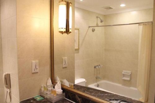 a bathroom with a shower and a tub and a sink at Datong Hotel in Datong