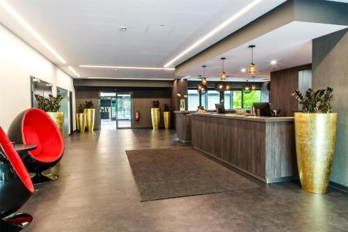 a lobby with a bar with red and yellow chairs at Best Western Plaza Hotel Mannheim in Mannheim