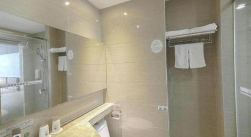 a bathroom with a shower and a sink and a mirror at GreenTree Alliance Shenzhen Shekou Sea World Hotel in Shenzhen