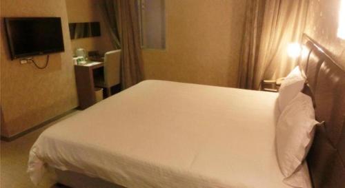 a hotel room with a white bed and a television at GreenTree Alliance Shenzhen Shekou Sea World Hotel in Shenzhen