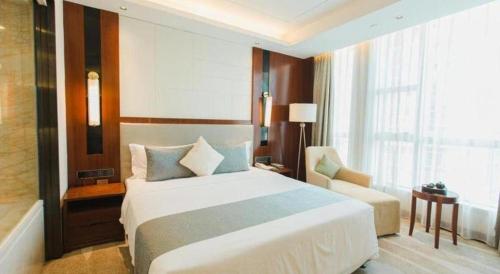 a hotel room with a large bed and a chair at Grand Soluxe Zhongyou Hotel Shenzhen in Shenzhen