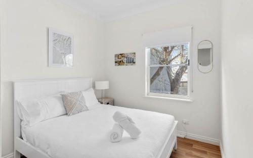 a white bedroom with a bed and a window at Sea Breeze at Smugglers Inn in Victor Harbor