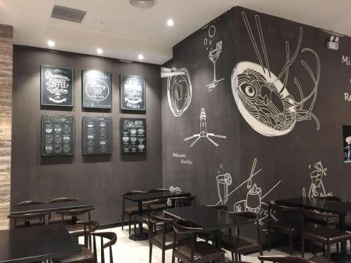 a dining room with tables and drawings on the wall at Landmark Hotel in Zhuhai
