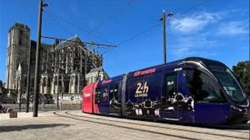 a blue and red train on the tracks near a building at Soft, cosy, élégant, centre-ville in Le Mans