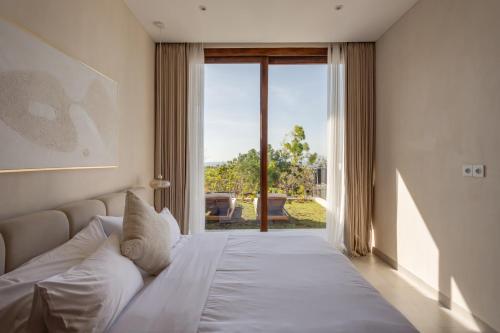 Un dormitorio con una cama blanca con una ventana grande. en New cozy 2-Bedroom Ocean View Villa, en Uluwatu